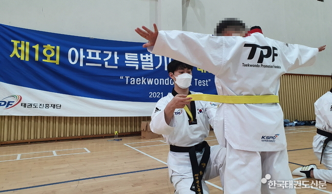 태권도봉사단원이 노란띠를 매어주고 있다.