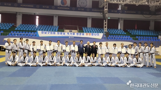 이동섭 국기원장(뒷줄 11번째)과 김형대 강남구 구의회 의장(뒷줄 10번째) 등 구의원 등 관계자들이 국기원 중앙수련장에서 태권체험 후 받은 명예단증을 펼쳐 보이고 있다. 김형대 구의회 의장은 명예 5단, 그 외 구의원들은 명예 4단을 받았다. 