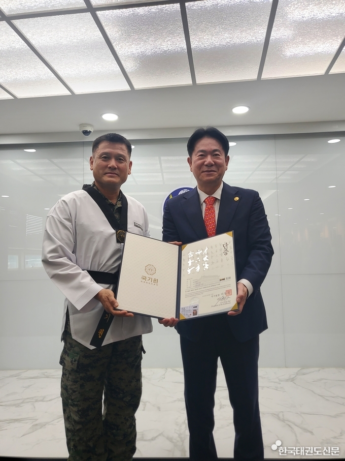 이동섭 국기원장(오른쪽)이 손식 특전사령관(왼쪽)에게 명예 6단증을 수여하고 기념 촬영하는 모습