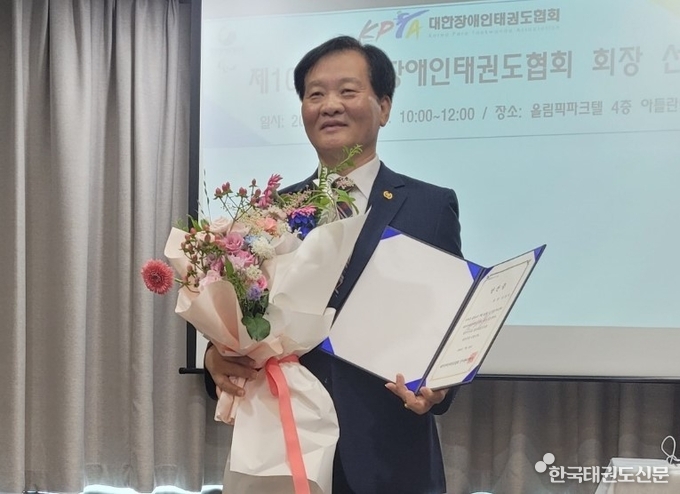 당선증과 꽃다발을 받고 밝은 표정을 하고 있는 김상익 회장