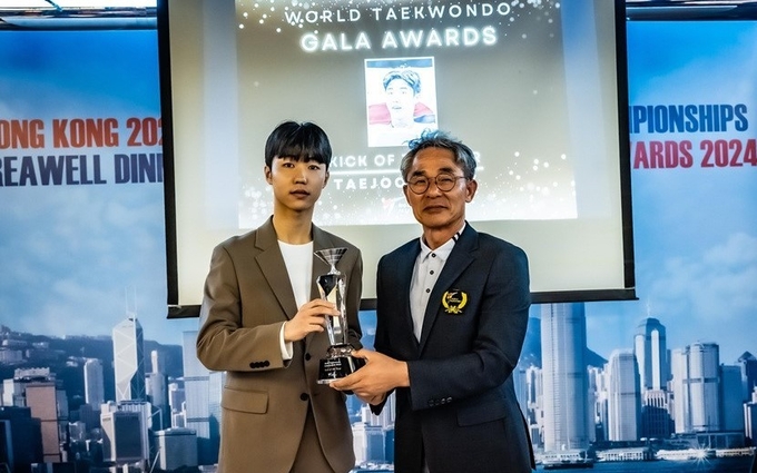 베스트킥을 수상한 박태준 선수(왼쪽)와 트로피를 수여하고 있는 정국현 세계태권도연맹 집행위원(우)