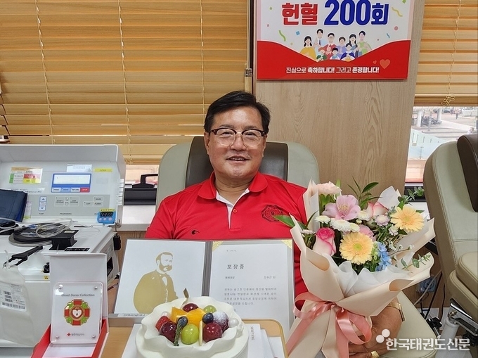 오수곤 대사범이 포장증과 꽃다발을 들고 활짝 웃는모습